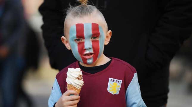 Small boy in soccer fan gear eating ice cream cone