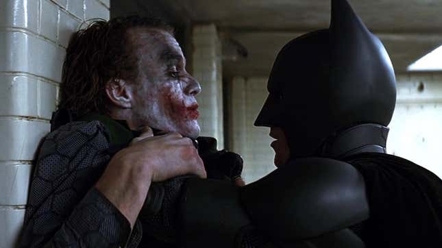 A screenshot from The Dark Knight. Batman menaces the Joker in a police interrogation room.