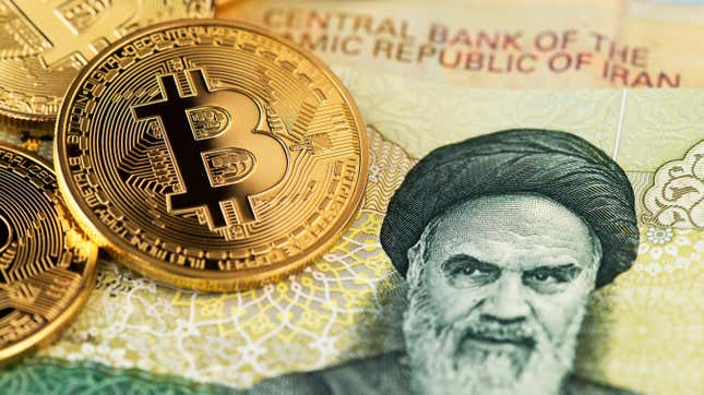 A few gold coins with the bitcoin symbol sitting atop Iranian currency with Ayatollah Khamenei's face.
