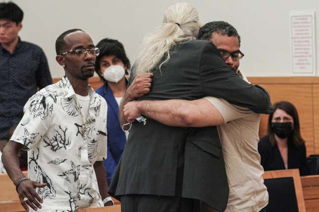 Vincent Ellerbe, left, approaches as Thomas Malik, right, embraces his lawyer Ron Kuby, center, following an exoneration hearing at Brooklyn Supreme Court, Friday July 15, 2022, in New York.