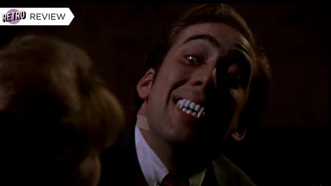 Nic Cage gives a bizarre smile with plastic vampire teeth in his mouth.