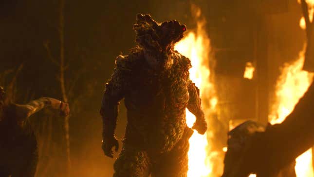 A hefty, menacing infected stands against a backdrop of flaming wreckage.