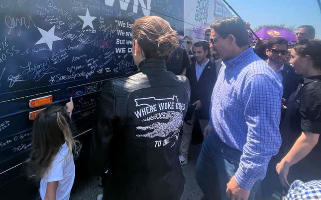 Casey DeSantis, center, the wife of presidential candidate Ron DeSantis, stands in front of the bus for her husband's super PAC, Never Back Down, on June 3, 2023, in Des Moines, Iowa.
