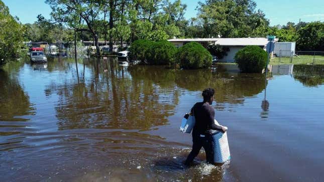 A man walks through a flooded street with his belongings in the Orlovista neighborhood following Hurricane Ian on October 1, 2022 in Orlando, Florida.