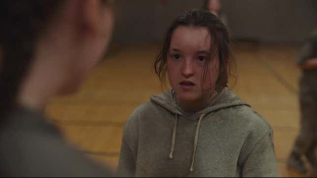 Ellie, in gym sweats, looks angrily at another girl in the foreground in a moment from HBO's The Last of Us.