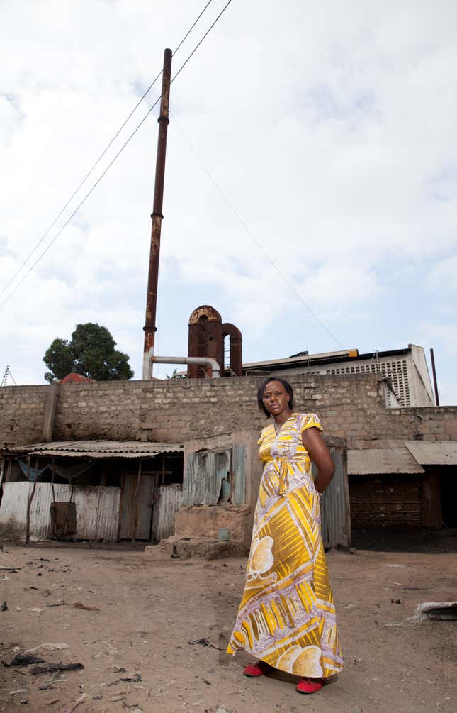 Phyllis Omido standing outside the lead battery smelter in Owino Uhuru, shortly after it shut down. Some residents used the smelter wall as the fourth wall of their houses.