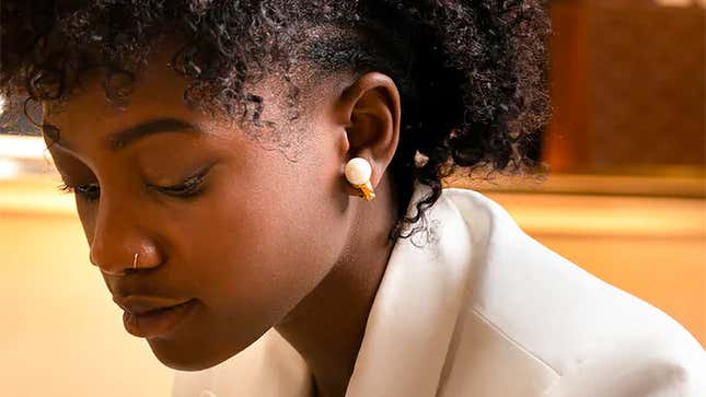 A person wearing the gold version of the Nova H1 Audio Earrings.