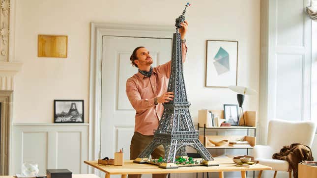 A man putting the top section on the Lego Eiffel Tower set.