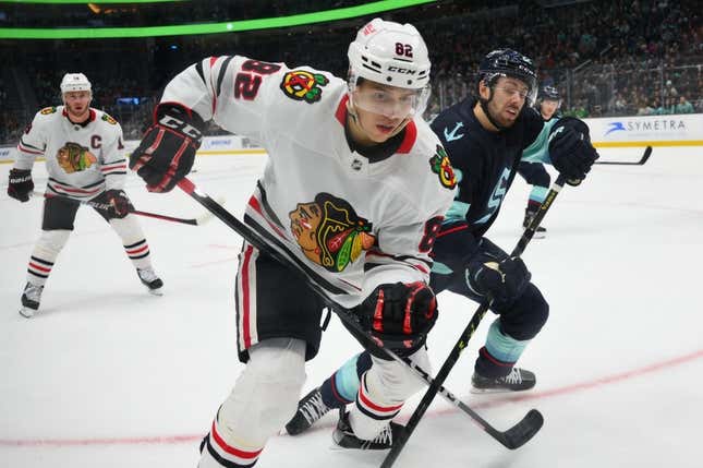 April 8, 2023; Seattle, Washington, USA; Chicago Blackhawks defenseman Caleb Jones (82) and Seattle Kraken right wing Oliver Bjorkstrand (22) battle for the puck in the second period of play at Climate Pledge Arena.