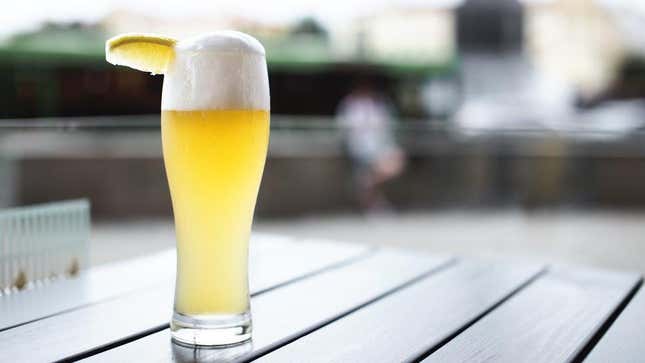Wheat beer with slice of lemon on patio table