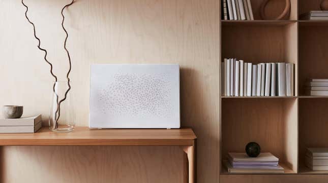 The white Symfonisk wall art speaker leaned against a wall on top of a table.