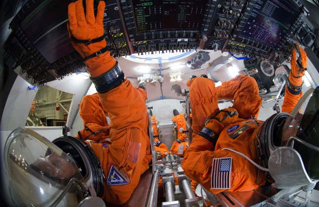 Spacesuit engineers demonstrate activities inside a mockup of the Orion spacecraft at NASA’s Johnson Space Center in Houston.