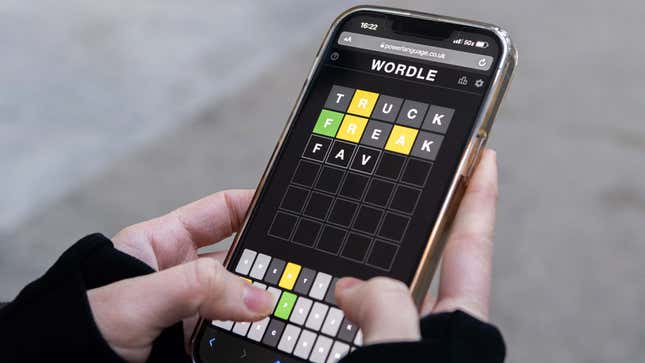 A close up photo of a woman playing Wordle on her phone. 