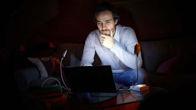 man working on a laptop with all the lights off