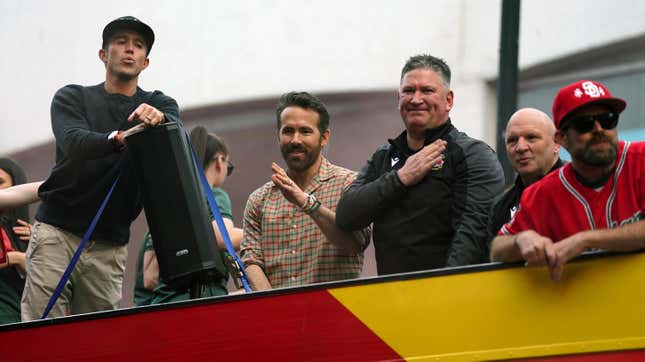 Wrexham co-owners Rob McElhenney and Ryan Reynolds celebrate on an open-top bus during a victory parade for the team.