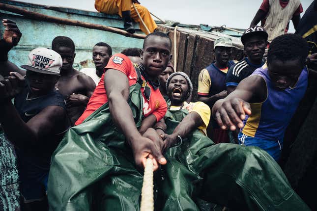 Local fishermen in Senegal cast their nets. Other than a motor and GPS, their boat lacks any modern equipment.