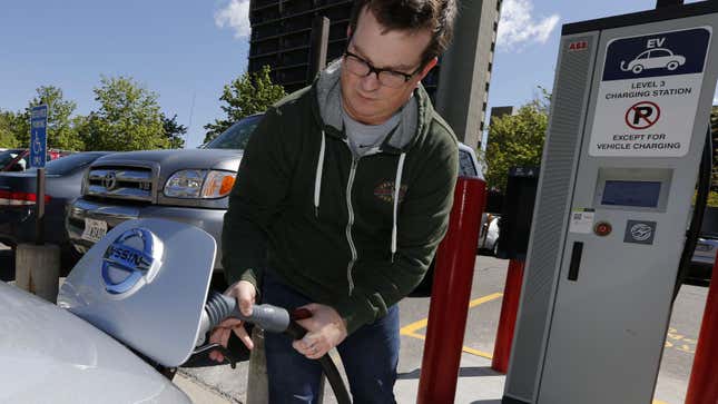 A man hooks up a charging cable so he can charge his 2013 Nissan Leaf electric car at ABB Inc.'s DC fast charging station in Salt Lake City
