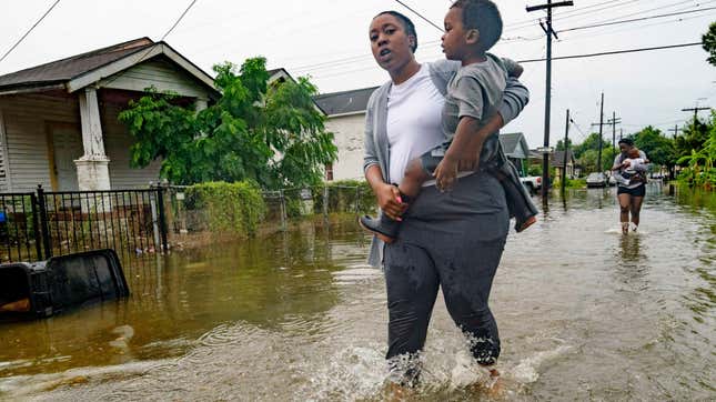 A woman carries a child through a flooded street in New Orleans on Wednesday, July 10, 2019.