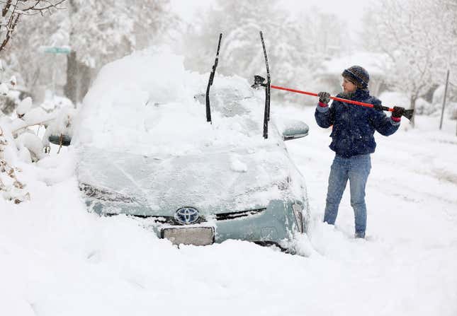 Cathy Morgan-Mace cleans snow and ice off her family’s car during a snowstorm in Salt Lake City, Utah, on Wednesday, Feb. 22, 2023.