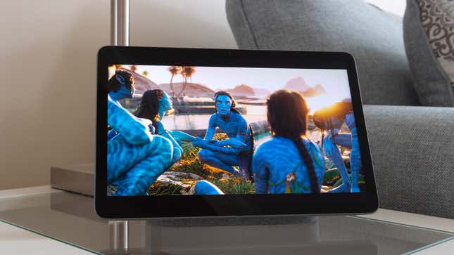 A scene from Avatar: The Way of Water playing on the Google Pixel Tablet's screen, with the device sitting on a small side table.