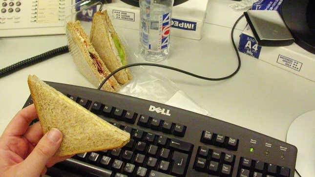 Person holds sandwich over computer keyboard