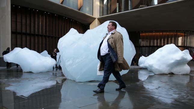 A man walks past a block of melting ice outside the Bloomberg building from an exhibit entitled ‘Ice Watch’ created by Icelandic-Danish artist artist Olafur Eliasson and leading Greenlandic geologist Minik Rosing.