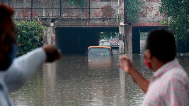 Local residents look at a submerged bus in a waterlogged road underpass after monsoon rainfalls in New Delhi

