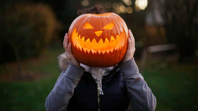 A girl with Halloween pumpkin in front of her head 