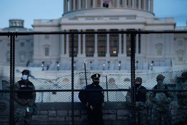 A Capitol Police officer stands with members of the National Guard behind a crowd control fence surrounding Capitol Hill a day after a pro-Trump mob broke into the US Capitol in Washington, DC.