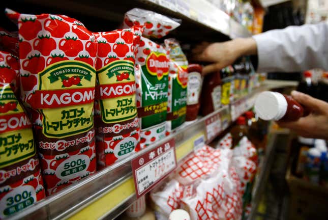Kagome's tomato ketchup bottles are displayed with their price tag as a staff arranges tomato ketchup bottles of other brands at Yoshiike supermarket in Tokyo