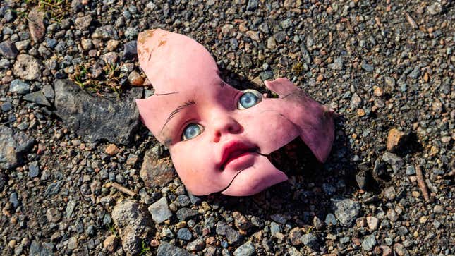 A photo shows a broken doll face lying on the ground. 