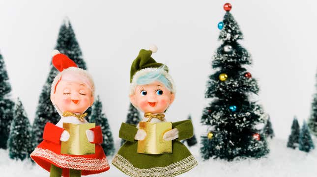 Vintage caroling figurines beside a Christmas tree