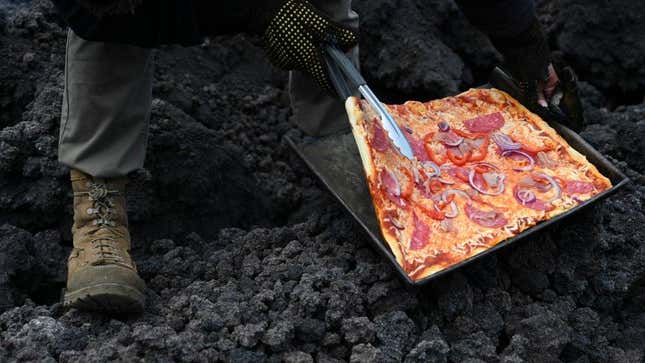 David Garcia checks a pizza he is cooking on the lava rivers that come down from the Pacaya volcano, May 2021