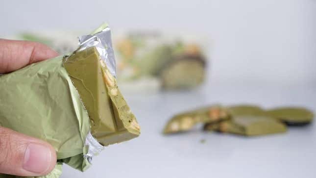 Hand holding matcha candy bar with nuts