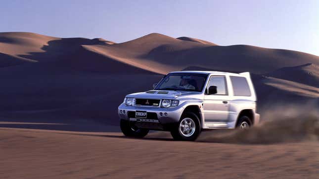 Image of a Mitsubishi Pajero Evolution drifting in a desert, kicking up sand.