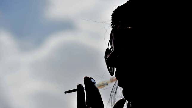 A silhouette of a woman smoking a cigarette. 