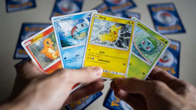 A man holds Pokemon cards for Charmandar, Squirtle, Pikachu, and Bulbasaur.