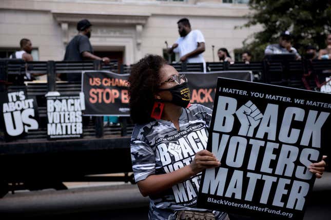 Demonstrators hold up signs during a live performance by the organization Long Live GoGo at a voting rights protest outside the U.S. Chamber of Commerce Headquarters on August 26, 2021, in Washington, DC.