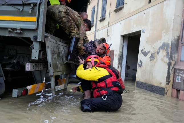 Photo of rescue workers pulling a man out of floodwaters