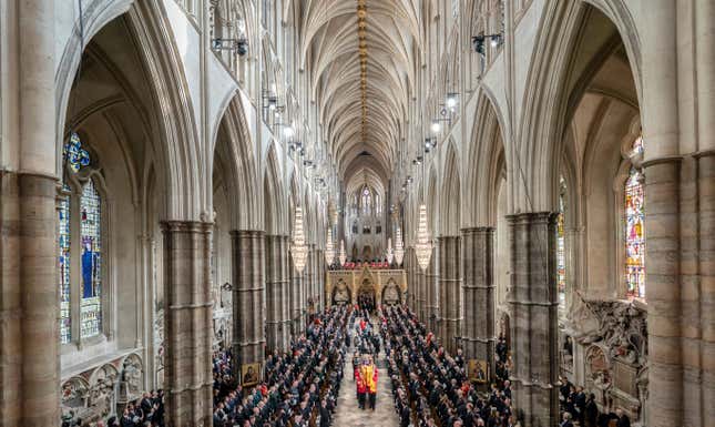 A symmetrical view of the main hall of Westminster Abbey. Members of the royal family follow follow behind the coffin of Queen Elizabeth II as it is carried out of the church.