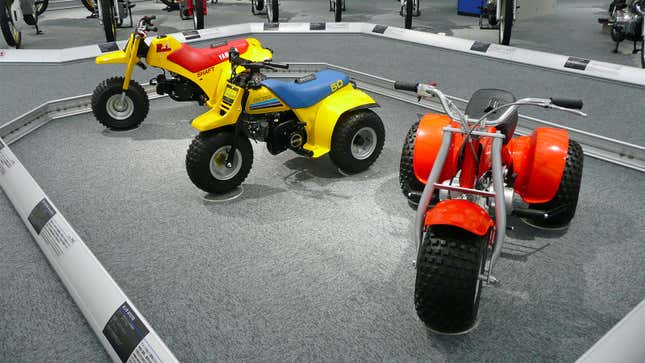 A photo of three off-road trikes parked in a museum. 