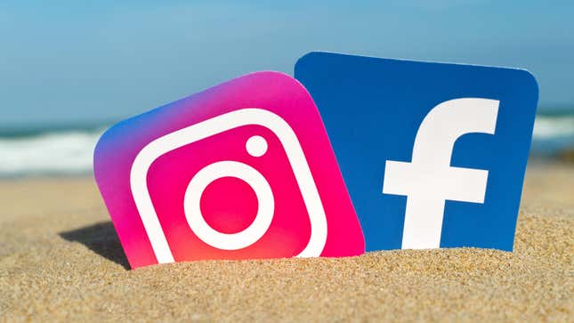 opular social media logos Instagram and Facebook printed on paper and placed in the sand against the sea.