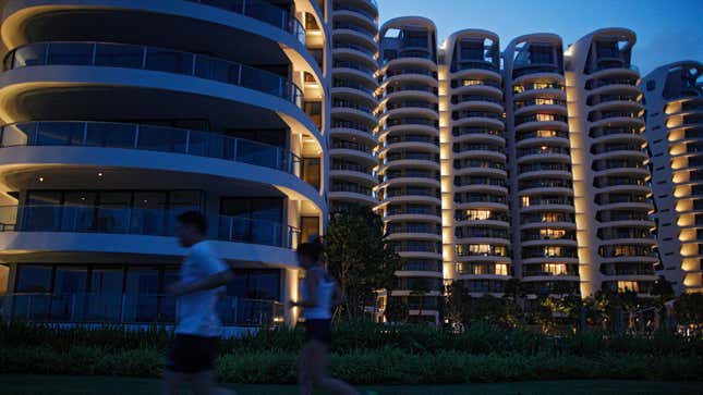 Joggers pass the largely vacant Cape Royale condominium in Sentosa Cove on Singapore's Sentosa island August 19, 2014. There's an eerie silence at night in Sentosa Cove, the man-made island resort billed as Singapore's answer to Monte Carlo and the only place in the country where foreigners can buy landed property. Dozens of houses - complete with their own private yacht berths and multiple swimming pools - sit empty while few lights are on in the apartment blocks overlooking the marina, a few kilometres away from Sentosa's giant casino. Picture taken August 19, 2014. To match SINGAPORE-PROPERTY/ REUTERS/Edgar Su (SINGAPORE - Tags: BUSINESS REAL ESTATE) - GM1EA8T0D6U01