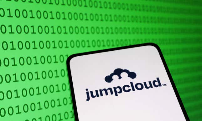 The JumpCloud logo is shown in black and white on a phone in front of a green background showing binary codes 