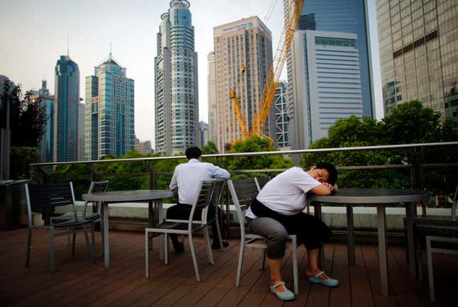 A waitress naps at a restaurant overlooking Shanghai’s financial district.