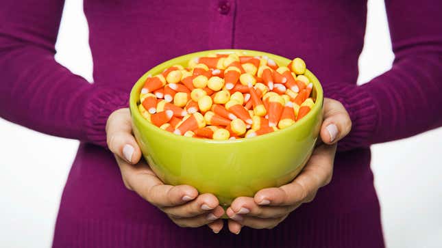 Hands holding a green bowl full of candy corn