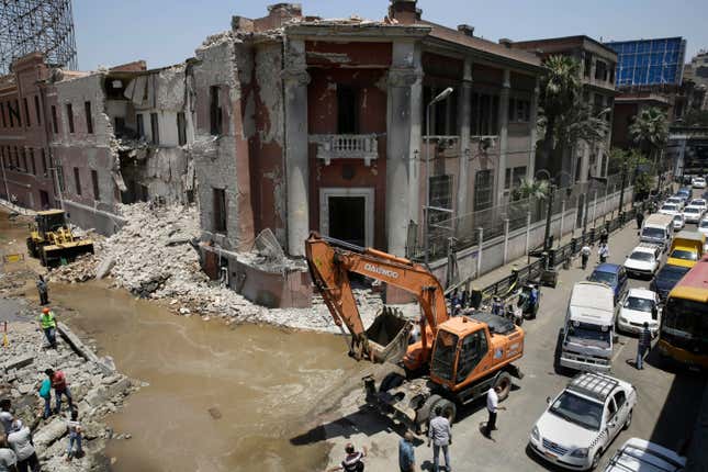 Workers clear rubble at the site of an explosion near the Italian Consulate in downtown, Cairo, Egypt.
