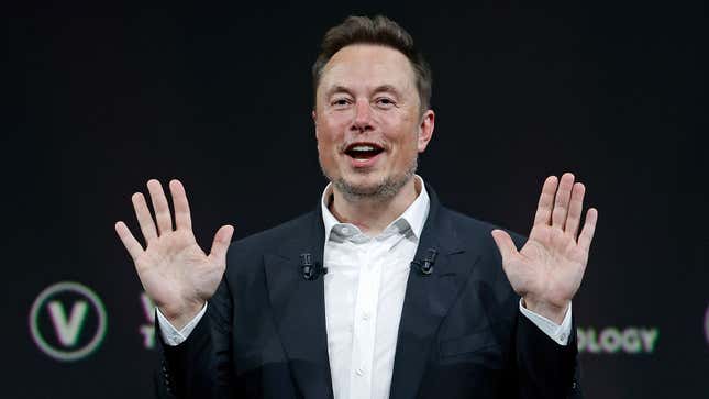 A photo of Elon Musk with his hands up. 