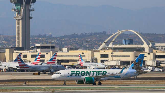 A Frontier Airlines aircraft taxing at LAX with several American Airlines planes in the background.