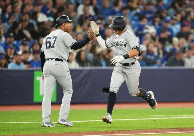 May 18, 2023; Toronto, Ontario, CAN; New York Yankees shortstop Anthony Volpe (11) hits a home run and celebrates with third base coach Luis Rojas (67) against the Toronto Blue Jays during the ninth inning at Rogers Centre.